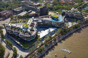 Vista aerea di un moderno complesso residenziale con diversi edifici, tetti verdi e un fiume adiacente alla proprietà.