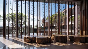 Un interior moderno con ventanas amplias, asientos de madera y un suelo reflectante.