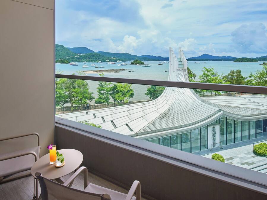 A balcony with a view of a modern building and a body of water with boats.