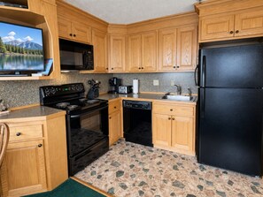 A compact kitchen with wooden cabinets, a black refrigerator, a stove, a dishwasher, and a microwave. - Beautiful Views New Deck Wi-Fi (Snowshoe)