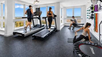 A gym with treadmills, a stationary bike, and a trampoline.