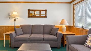 A living room with a sofa, ottoman, and two lamps.