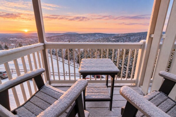 A balcony with a table and chairs, overlooking a snowy landscape during sunset. - Beautiful Views New Deck Wi-Fi (Snowshoe)