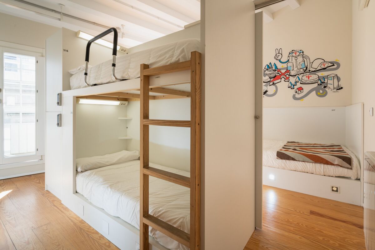 Quarto em dormitório com beliches, escada de madeira e painel decorativo na parede.