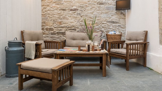 A cozy outdoor seating area with wooden furniture and a stone wall backdrop.