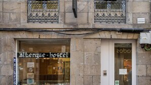 A hostel with a large window displaying various items. There is a door with a sign above it.
