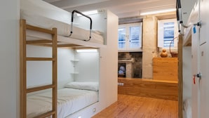 A compact room with bunk beds, a small kitchenette, and a window with a view.