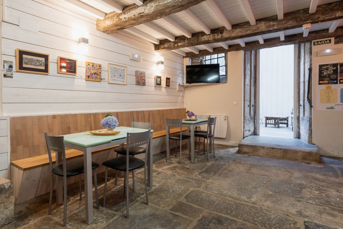 A dining area with wooden walls, stone flooring, and a television mounted on the wall.