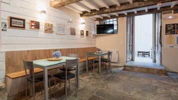 A dining area with wooden walls, stone flooring, and a television mounted on the wall.
