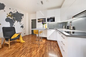 A modern kitchen with white cabinets, stainless steel appliances, and a wooden floor. - Stylish Apartment in Prague 1 Close to Old Town Square by EasyBNB Premium (Prague)