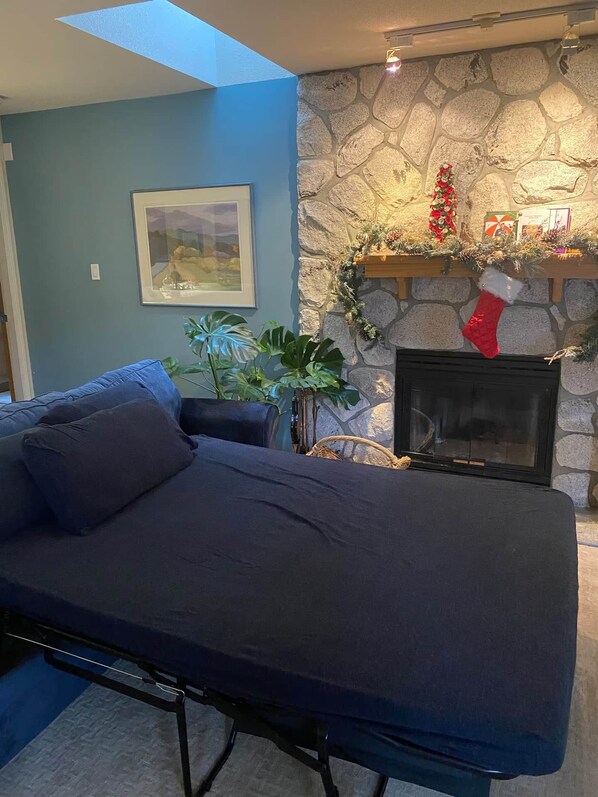 A living room with a stone fireplace, a couch, a framed picture, and a Christmas stocking.