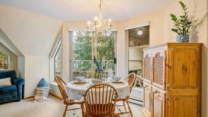A dining area with a round table, chairs, a chandelier, and a wooden cabinet.