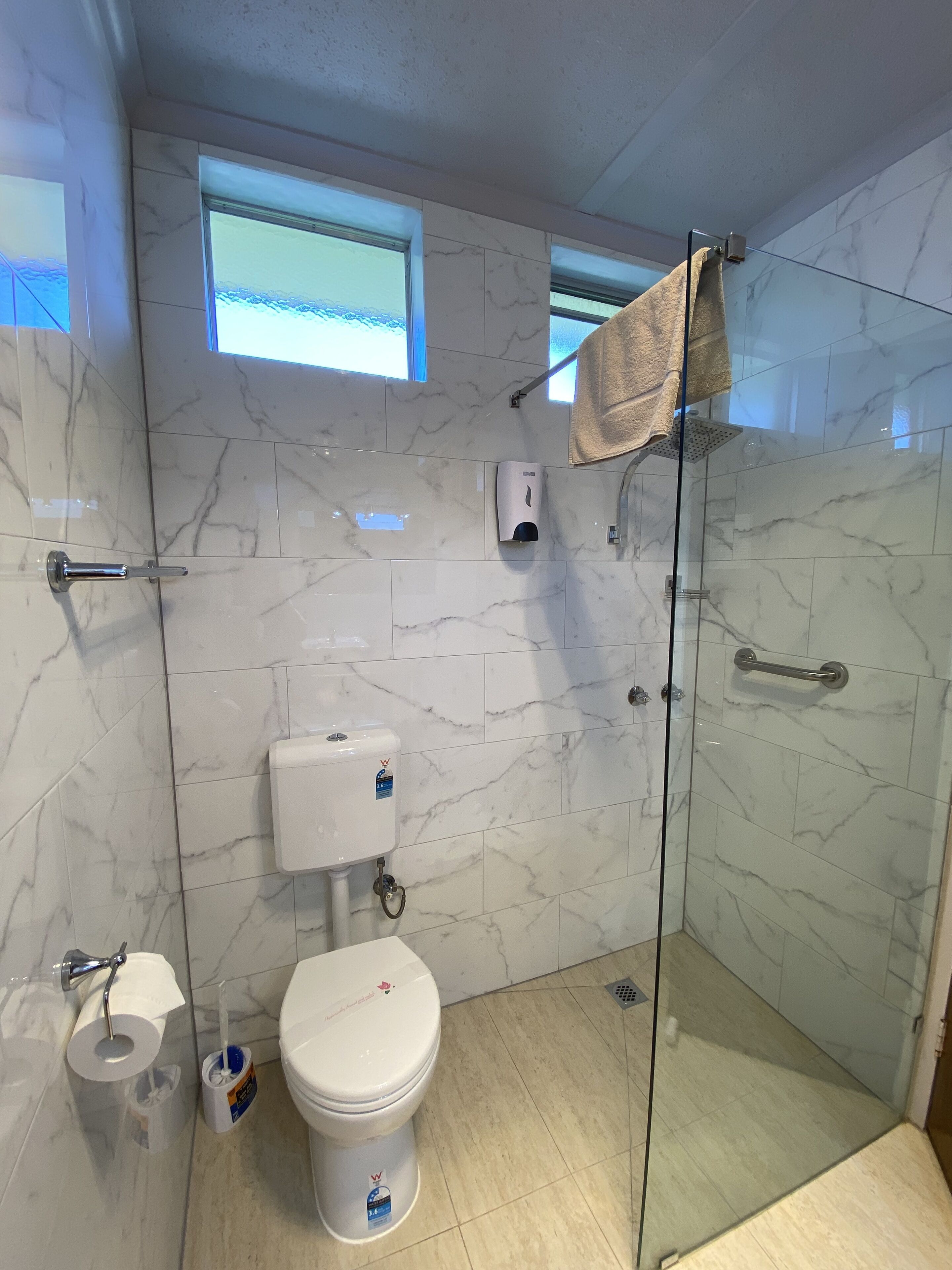 A modern bathroom with a glass-enclosed shower, a toilet, and a bidet.