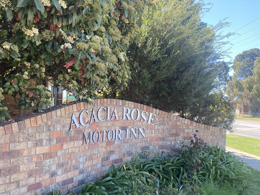 Un muro de ladrillo con el letrero "Acacia Rose Motor Inn".