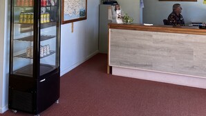A reception area with a glass display case, a map, a framed picture, and a ceiling fan.
