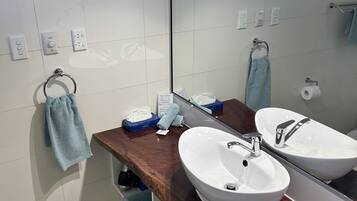 A bathroom with two sinks, a mirror, and a towel rack.