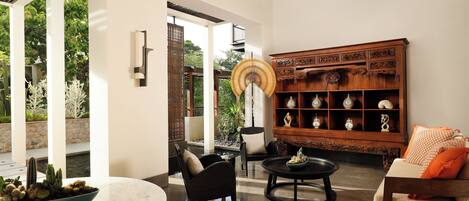 A modern living room with a sofa, armchairs, a coffee table, and a decorative wooden cabinet.