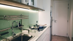 A modern kitchen with stainless steel appliances, a built-in oven, and a microwave on a shelf. - Studio - Serviced Apartment Sea View - Isla Melocotón Ven67 Phu Quoc (Thành phố Phú Quốc)