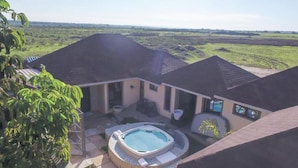 A house with a swimming pool, surrounded by a large lawn and a view of the countryside.