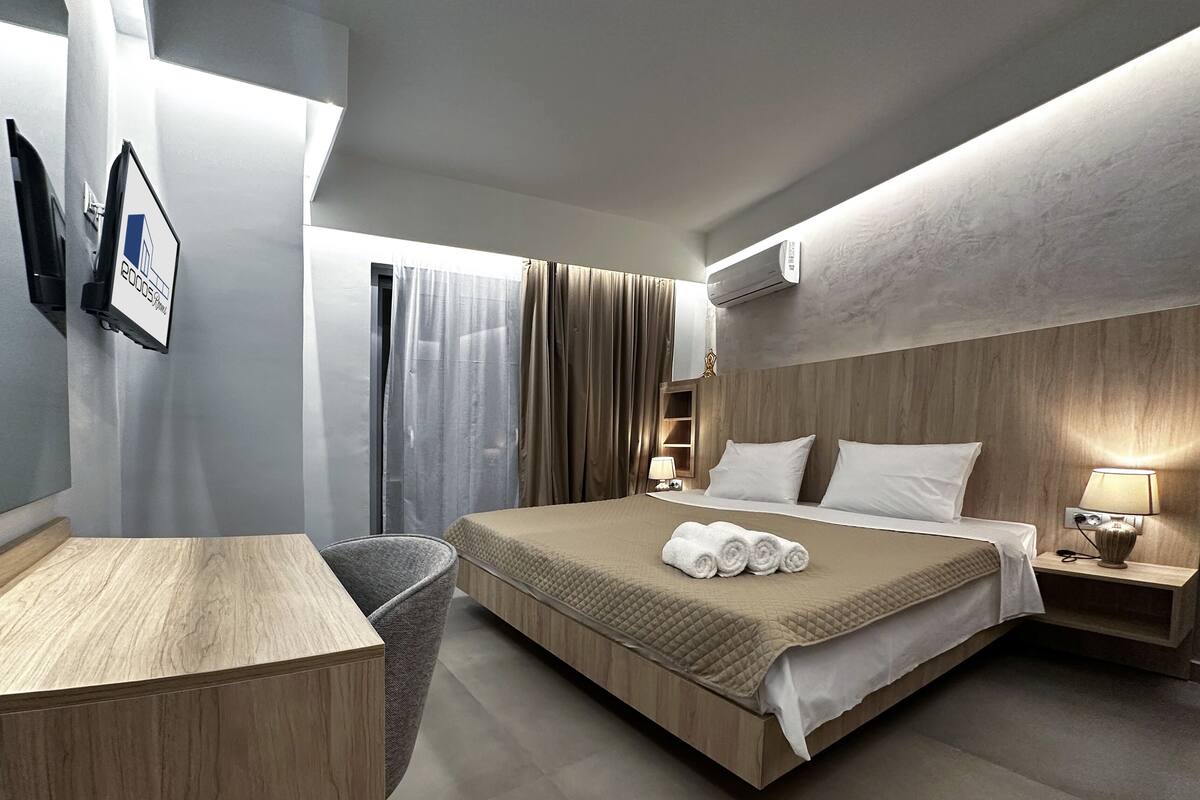 A modern hotel room with a large bed, a desk, and a chair.