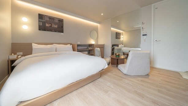 A modern hotel room with a large bed, bedside tables, a chair, and a mirror. - Anook Thepeak Hotel Incheon Songdo (Incheon)