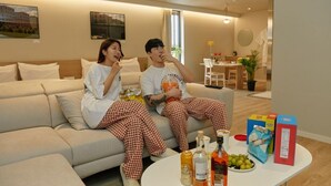 A couple sitting on a sofa in a modern living room with a dining area in the background. - Anook Thepeak Hotel Incheon Songdo (Incheon)