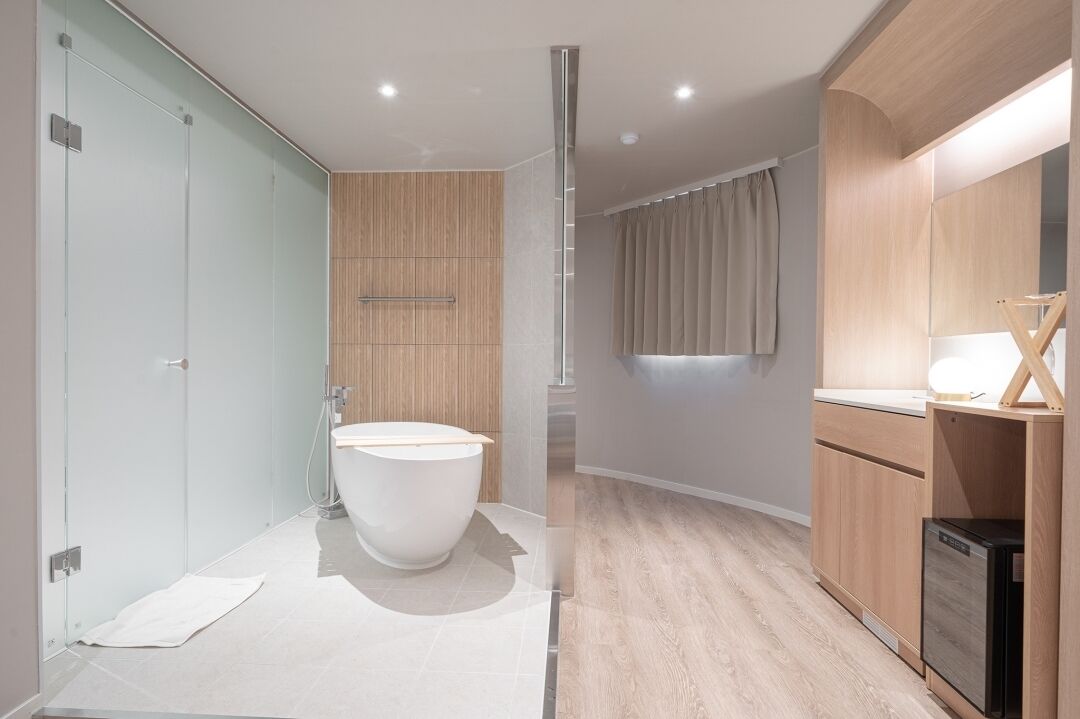 A modern bathroom with a large bathtub, a glass shower enclosure, and wooden cabinetry.