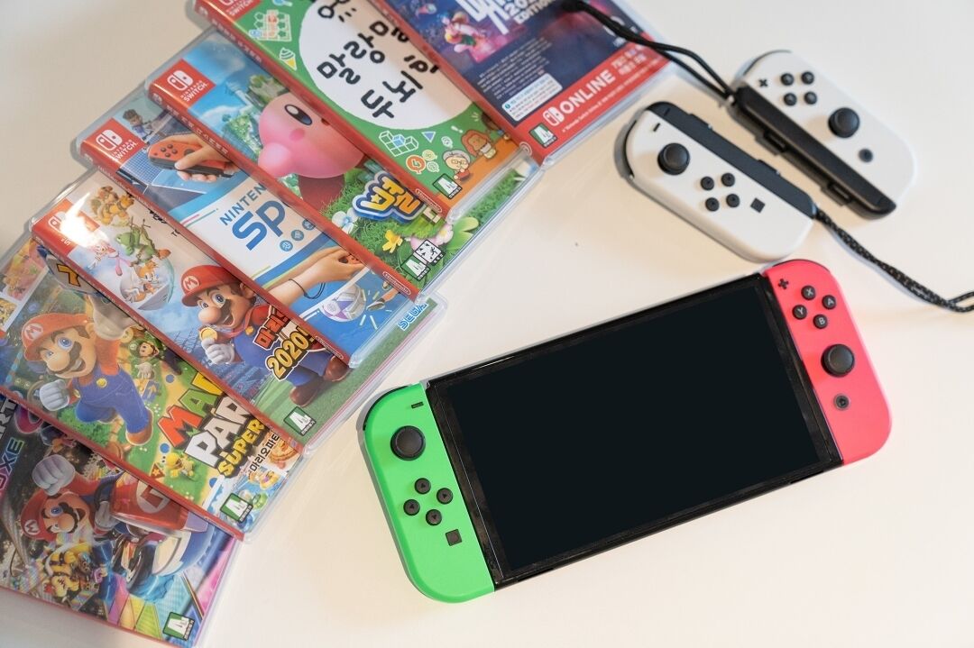 A Nintendo Switch console with two game cases, one of Mario Kart 8 Deluxe and another of Super Mario Bros.