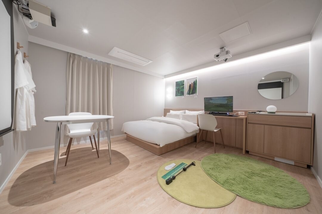 Une chambre d’hôtel moderne équipée d’un lit, d’un bureau, d’une chaise, d’une télévision et d’un miroir.