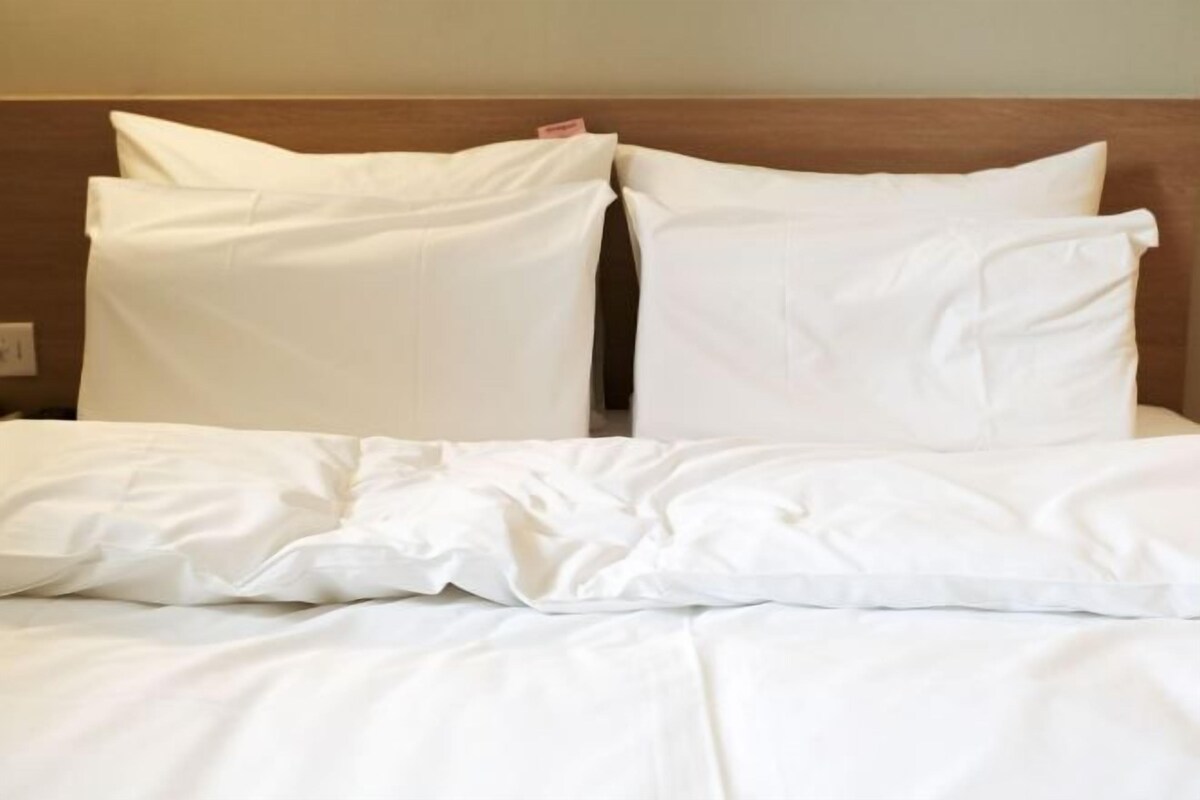 A neatly made bed with white bedding and pillows.