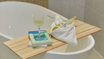 A bathtub with a book and a glass of wine on a wooden tray.