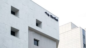 A modern building with a minimalist facade, featuring three rectangular windows and a prominent sign. - Anook Thepeak Hotel Incheon Songdo (Incheon)