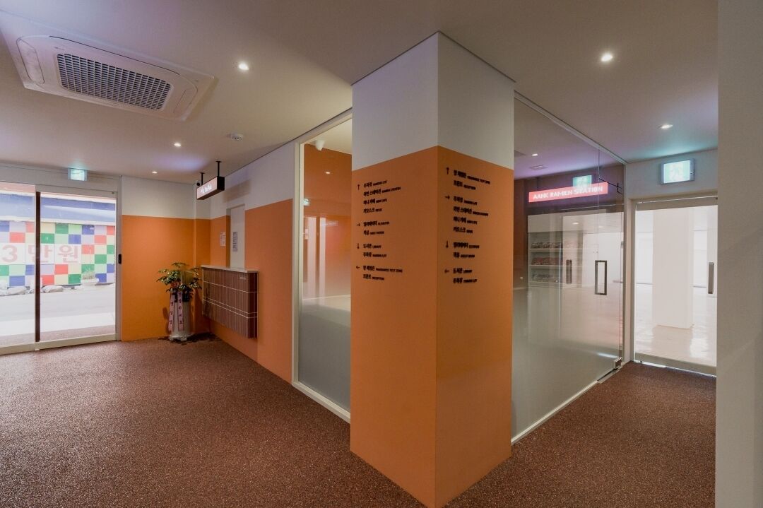 Un pasillo moderno de hotel con puertas de vidrio, una zona de recepción y un diseño de pared colorido.
