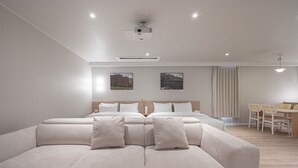 A modern hotel room with a large bed, a sofa, a dining area, and two framed pictures on the wall. - Anook Thepeak Hotel Incheon Songdo (Incheon)