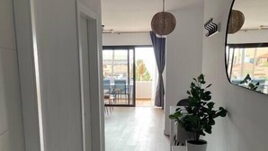Un pasillo moderno con una planta en maceta, un cuenco de cristal y un espejo grande en la pared.
