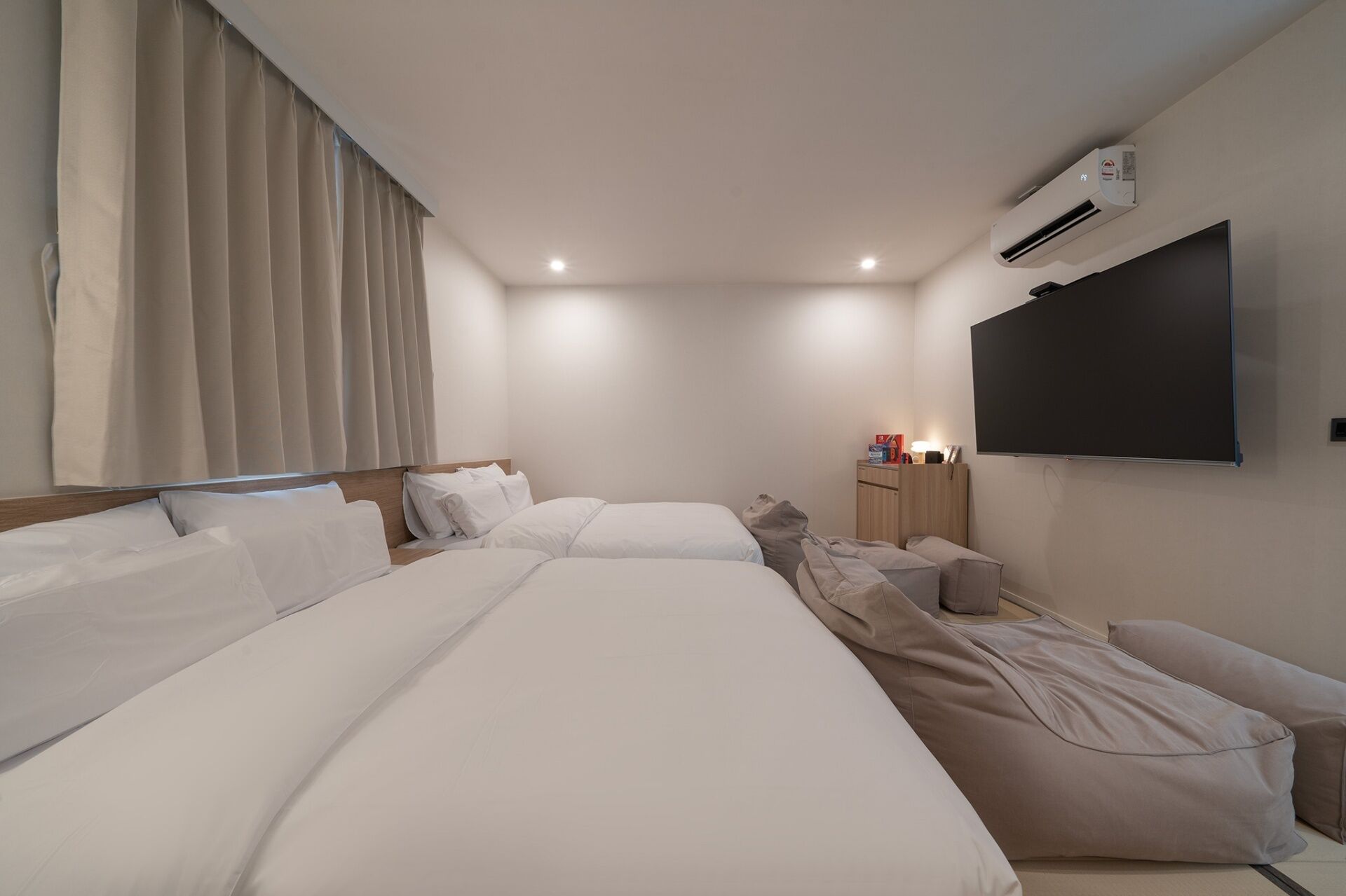 Een hotelkamer met twee bedden, een flatscreen televisie, een airconditioning en een nachtkastje met een lamp.