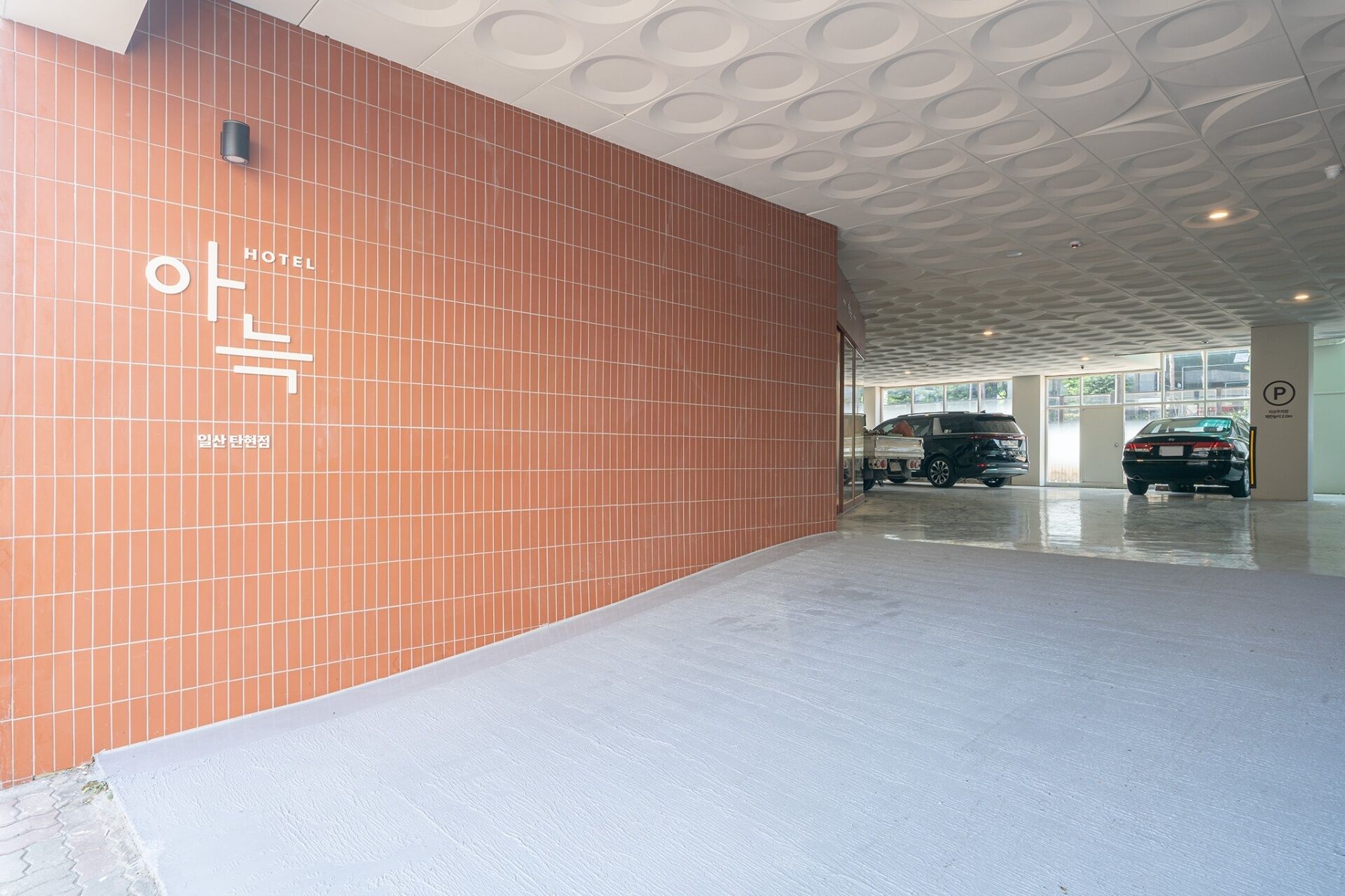 A modern hotel entrance with a tiled wall and a ceiling with circular patterns.