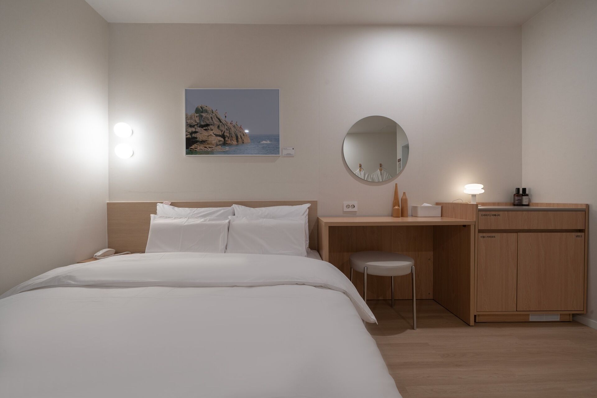 Habitació d'hotel amb llit, escriptori, cadira, mirall i un petit armari.