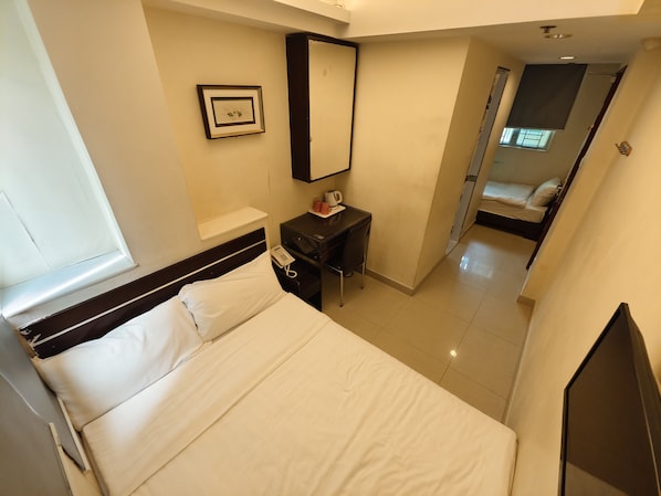 Une chambre d’hôtel comprenant un lit, une table de chevet, un miroir, un petit bureau et un téléphone.