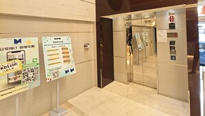 An elevator interior with a digital display, a handrail, and a door with a safety sign. - Metacity MK (Kowloon)