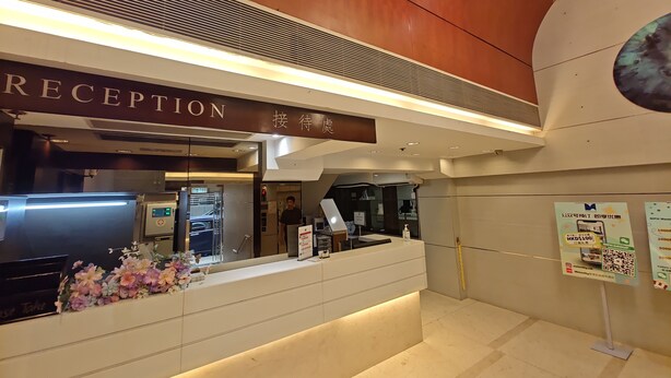A reception area with a sign reading "RECEPTION" and a digital display. - Metacity MK (Kowloon)