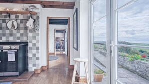 Eine moderne Küche mit kariertem Fliesenspiegel, Holzbalken und einem großen Fenster mit Blick auf eine schöne Landschaft.