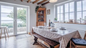 Ein Essbereich mit einem Tisch für vier Personen, einem Holzschrank mit Glastüren und Blick durch große Fenster.