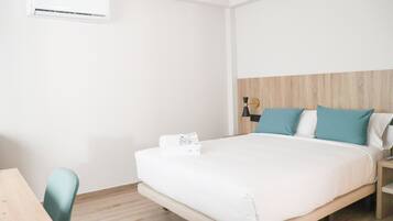 Ein Hotelzimmer mit einem Bett, einem Holz-Kopfteil, einem Nachttisch, einem Schreibtisch und einer Klimaanlage.