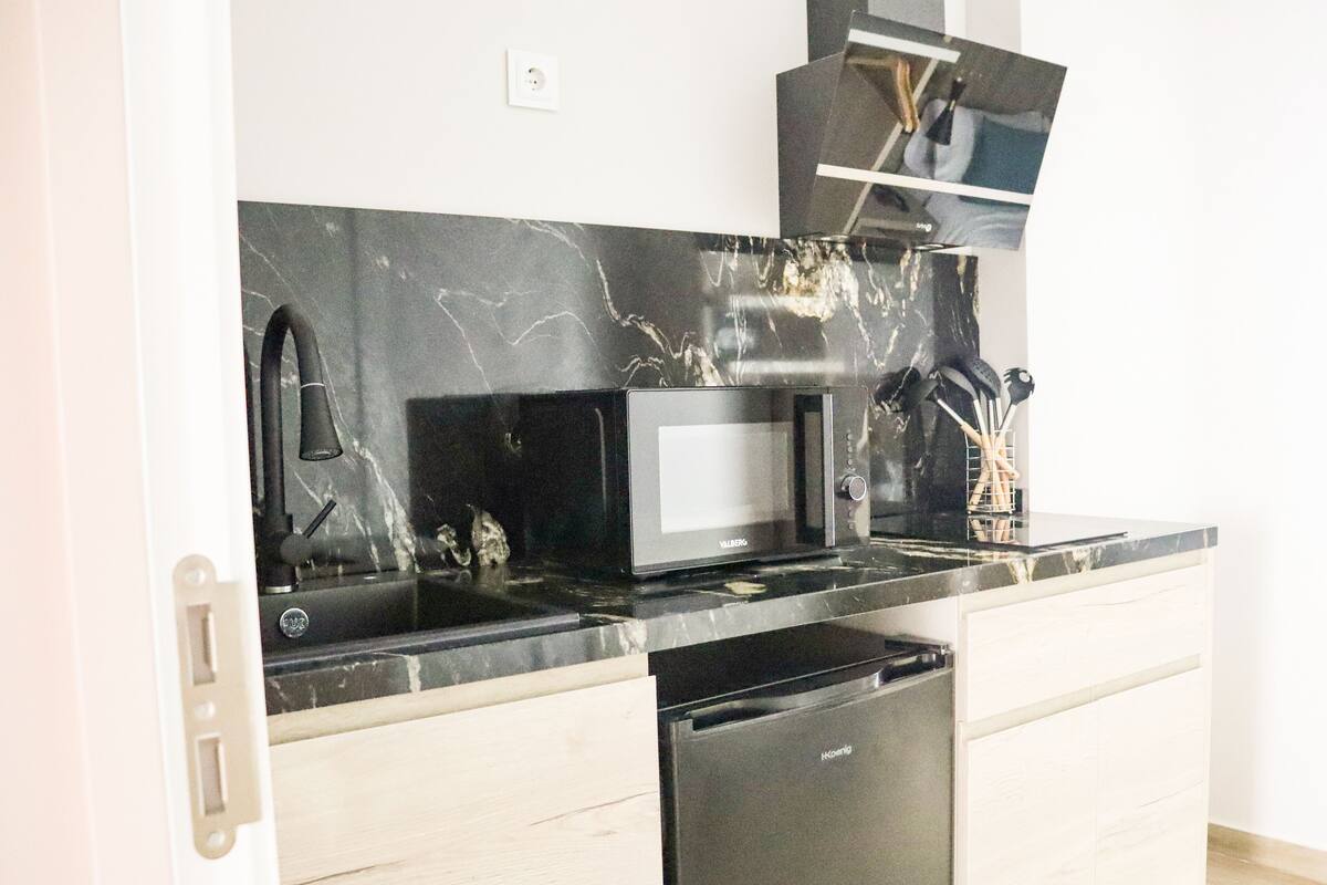 A kitchen with a black microwave, a sink, and a dishwasher.