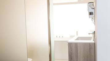 Une salle de bain moderne équipée de toilettes, d’un lavabo et d’un sèche-cheveux fixé au mur.