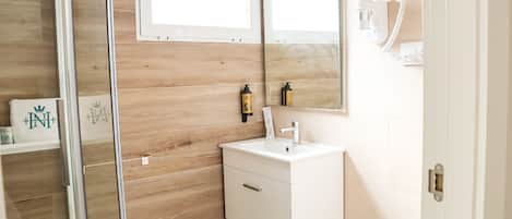 Une salle de bain avec un mur en bois, un lavabo blanc et une cabine de douche en verre.