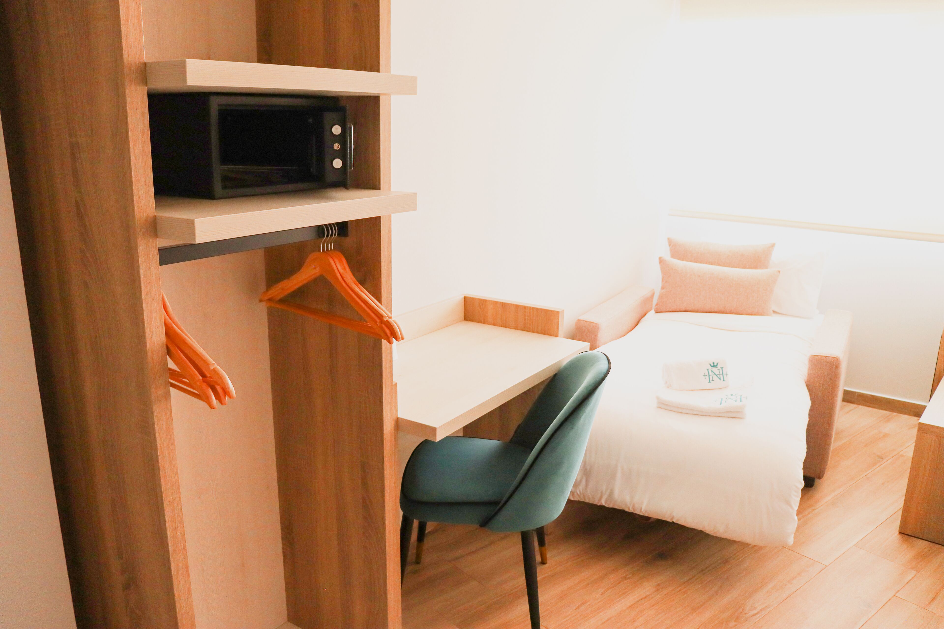 Una habitación de hotel compacta con una cama, un escritorio, una silla, un microondas y un armario.