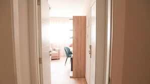 Un pasillo que conduce a una habitación con una cama, una silla y un armario de madera.