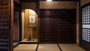 A traditional Japanese room with tatami flooring, a sliding door, and a hanging picture. - Rinn Shijo Machiya (Kyoto)
